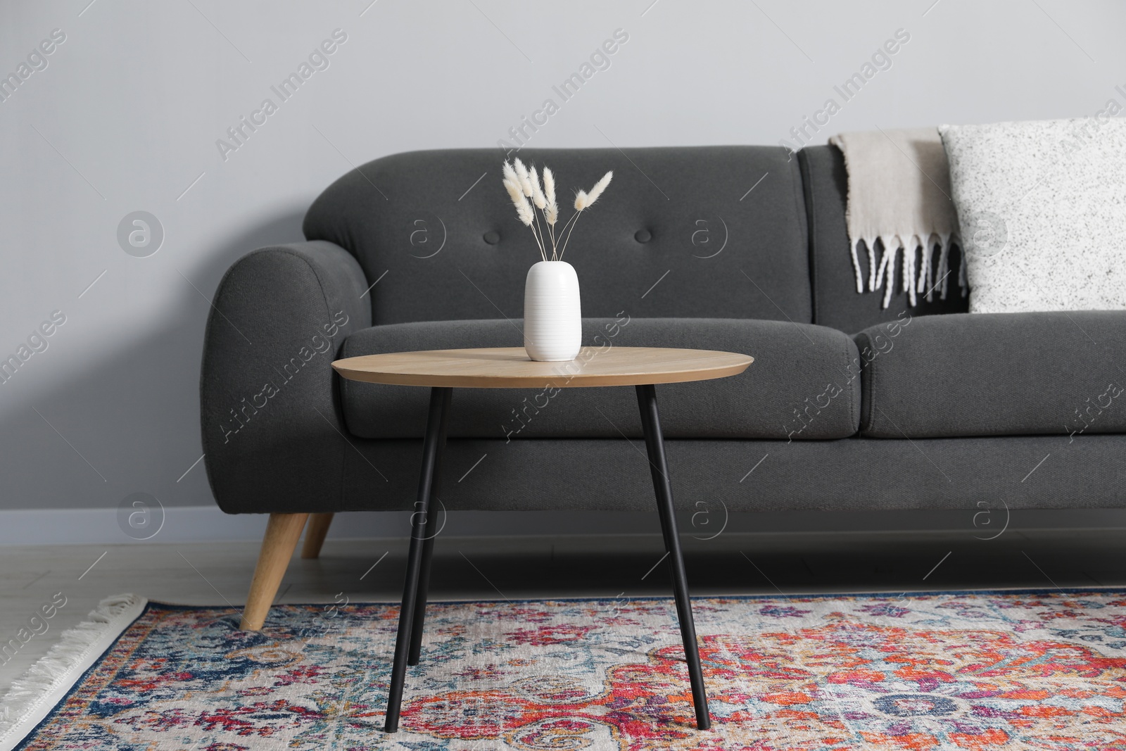 Photo of Comfortable sofa and table near grey wall in room