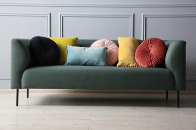 Stylish sofa with cushions near grey wall