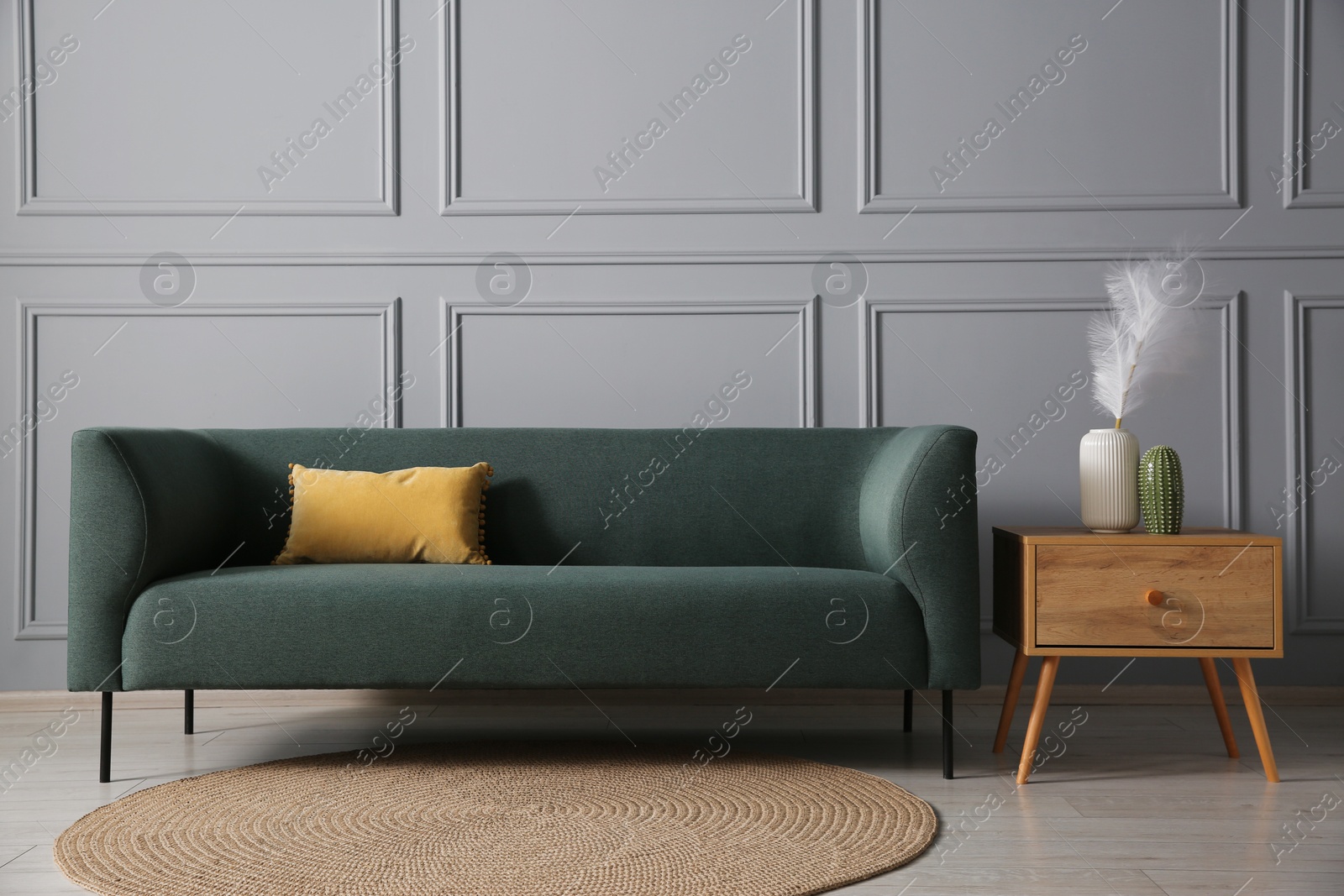 Photo of Comfortable sofa and side table near grey wall in room