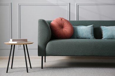 Photo of Comfortable sofa and side table near grey wall in room