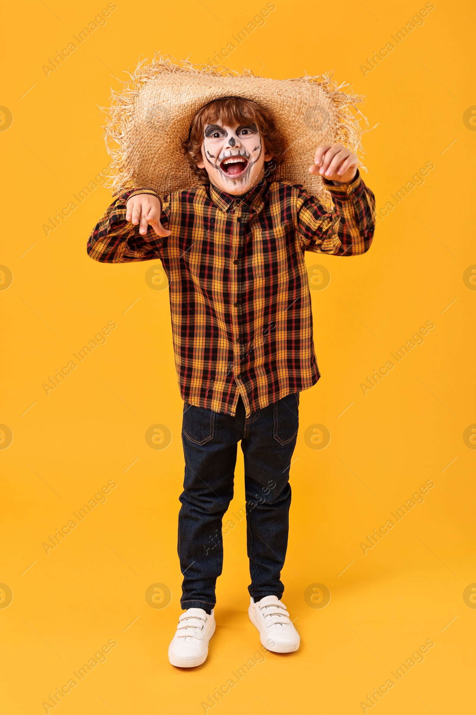 Photo of Funny boy dressed like scarecrow on yellow background. Halloween celebration