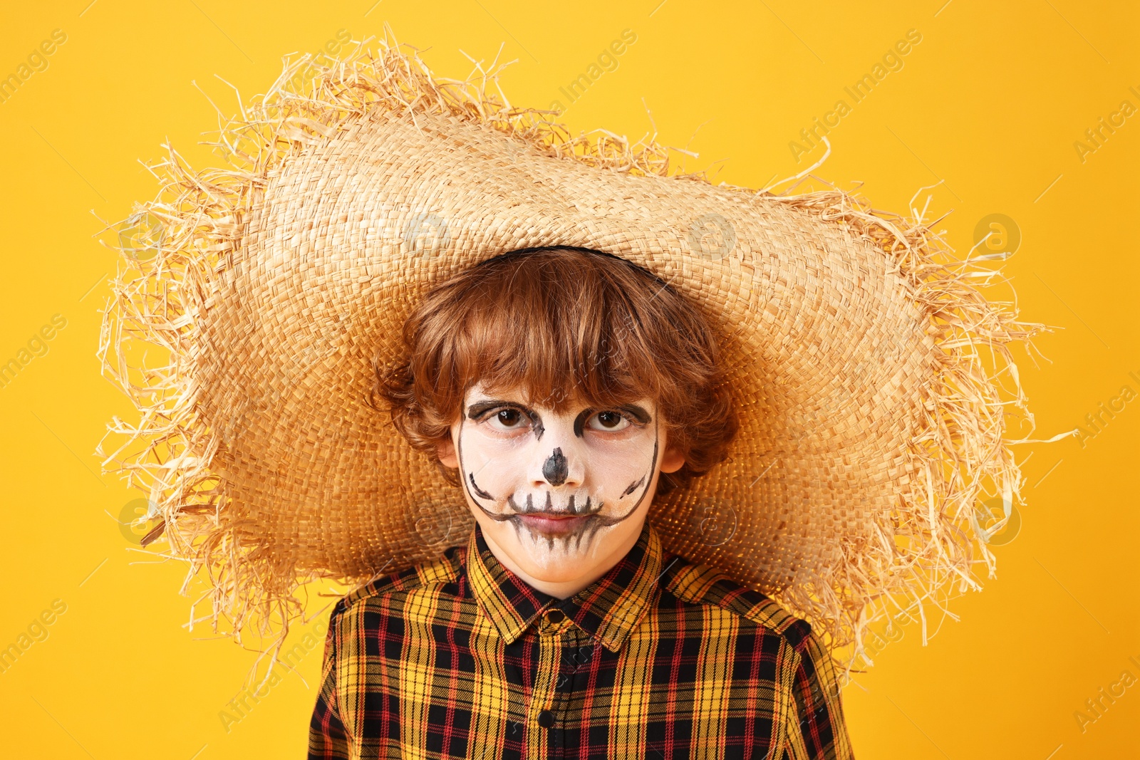 Photo of Funny boy dressed like scarecrow on yellow background. Halloween celebration