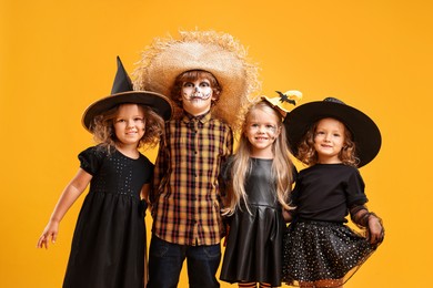 Photo of Cute children wearing Halloween costumes on orange background