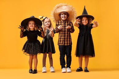 Photo of Cute children wearing Halloween costumes on orange background