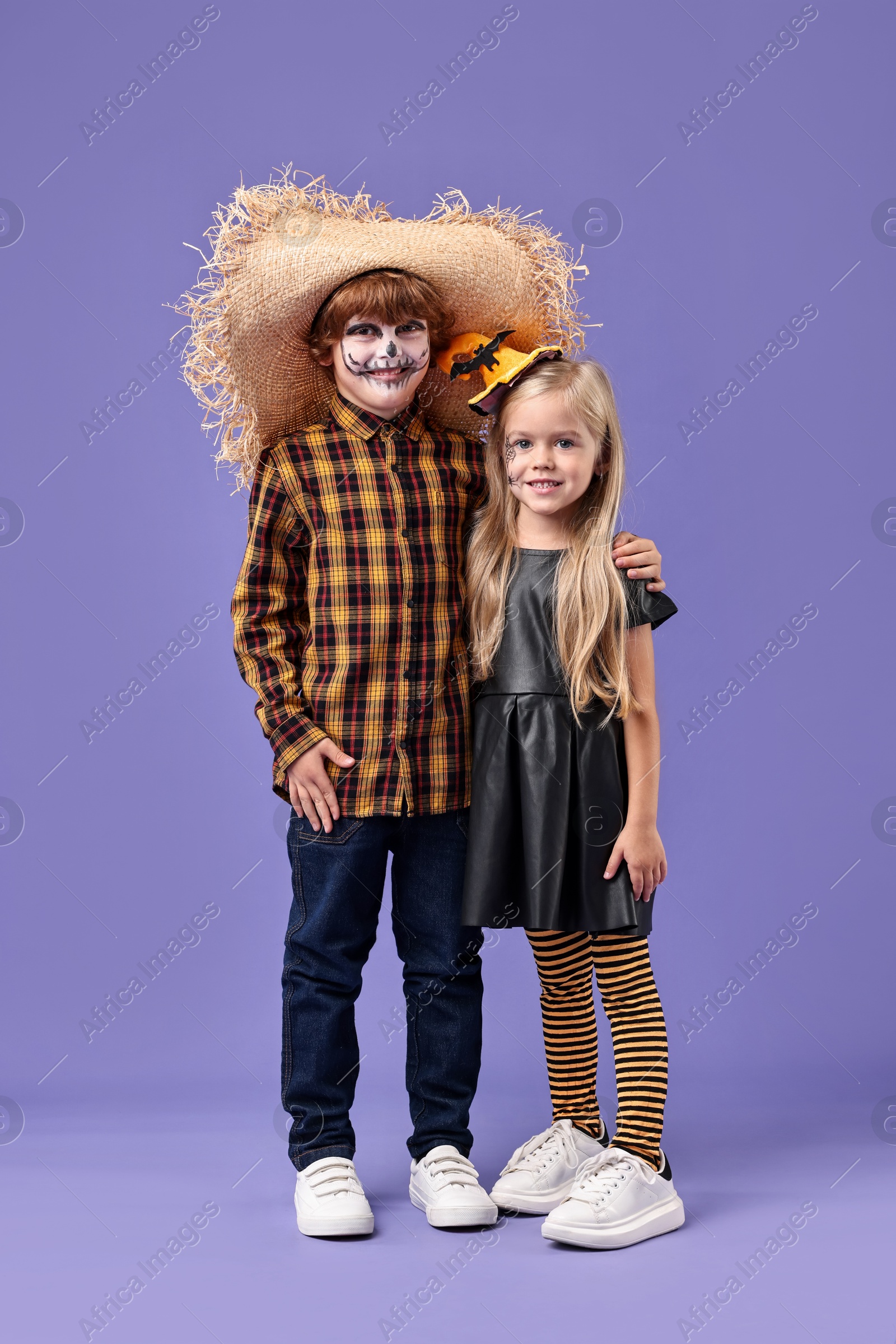 Photo of Cute children wearing costumes on violet background. Halloween celebration