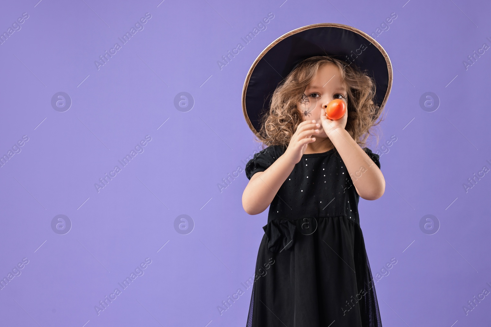 Photo of Funny girl with air balloon dressed like witch on violet background, space for text. Halloween celebration