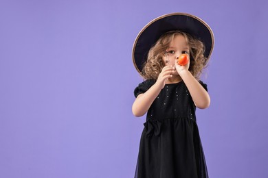 Photo of Funny girl with air balloon dressed like witch on violet background, space for text. Halloween celebration