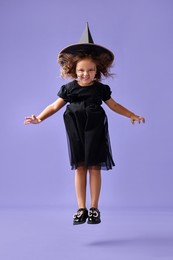 Funny girl dressed like witch for Halloween celebration on violet background