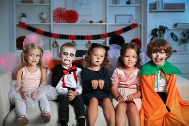 Photo of Funny children wearing costumes for Halloween celebration in room