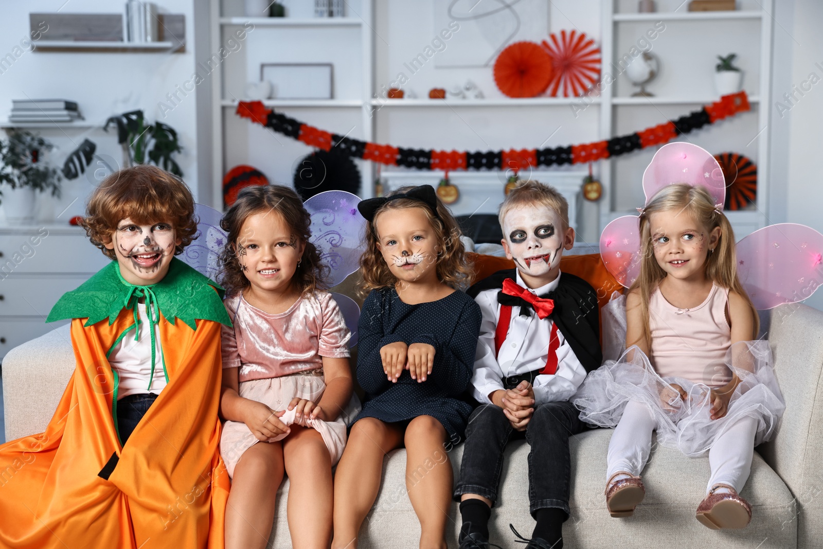 Photo of Funny children wearing costumes for Halloween celebration in room