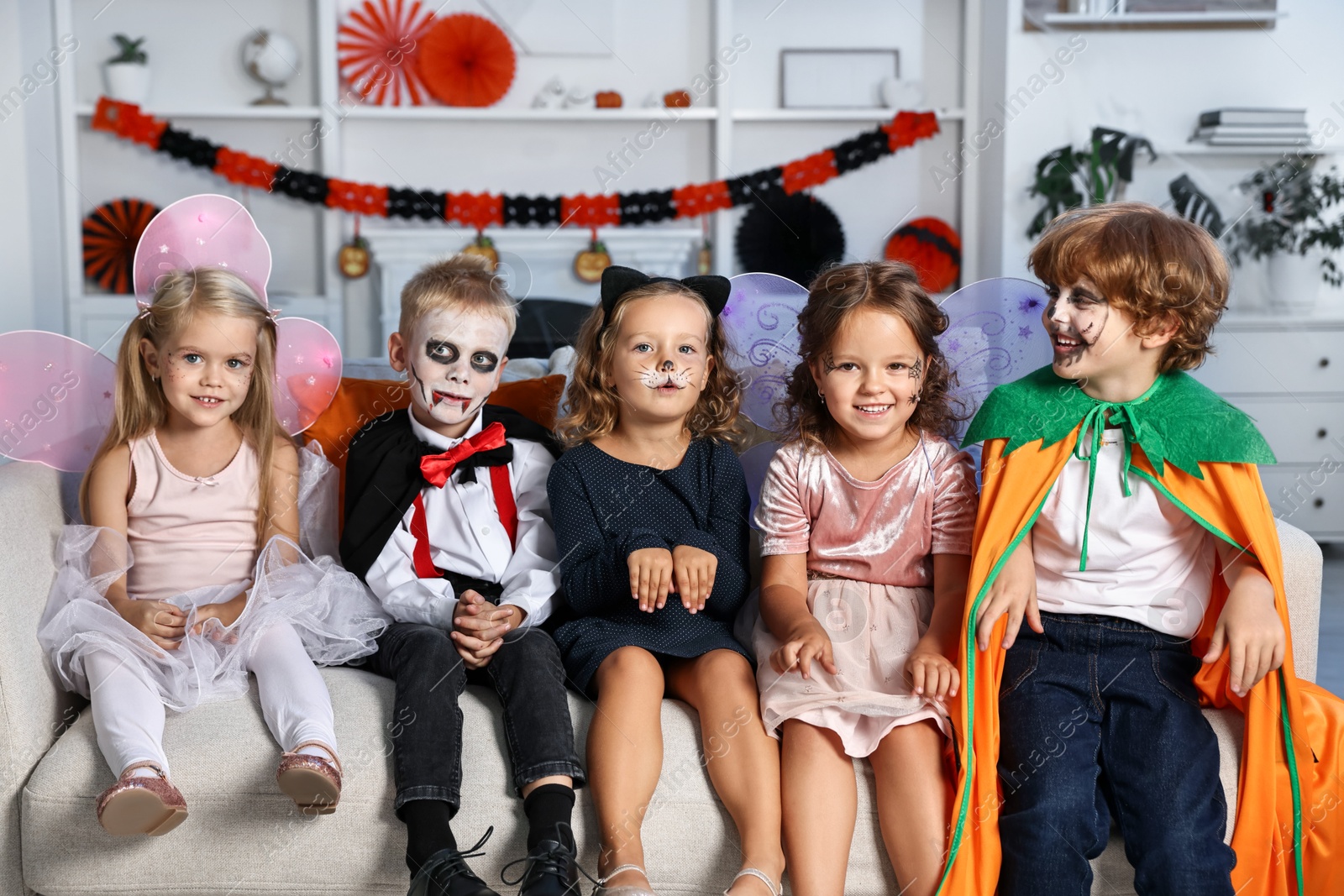 Photo of Funny children wearing costumes for Halloween celebration in room