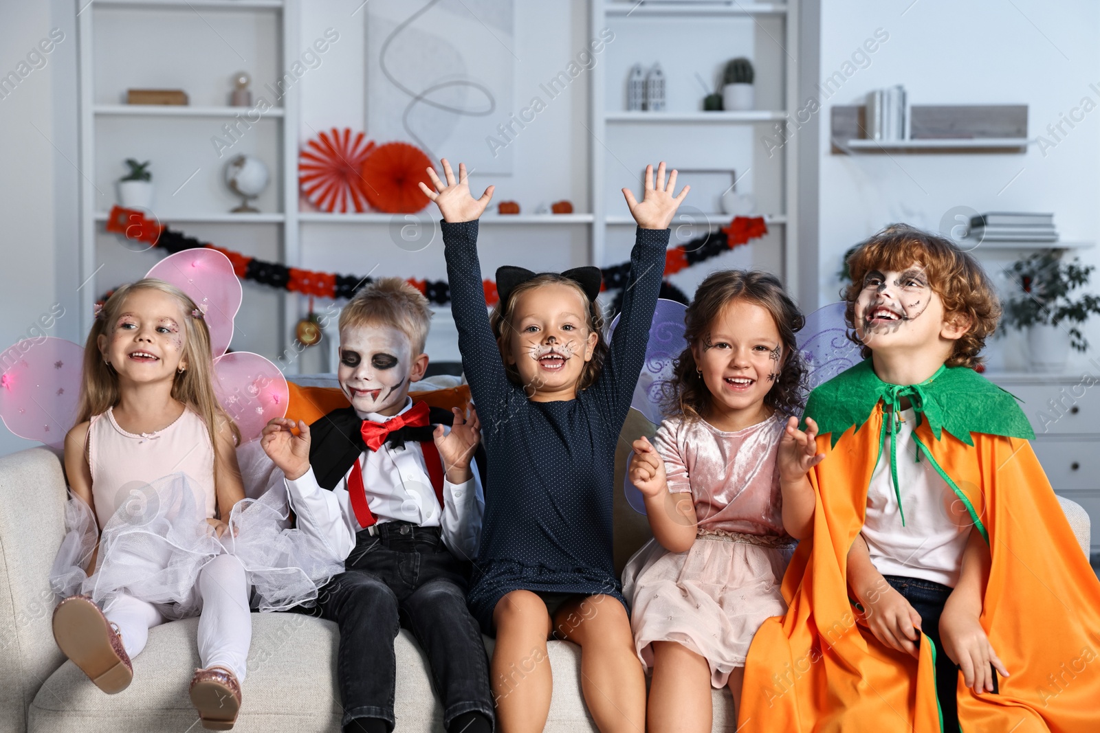 Photo of Funny children wearing costumes for Halloween celebration in room