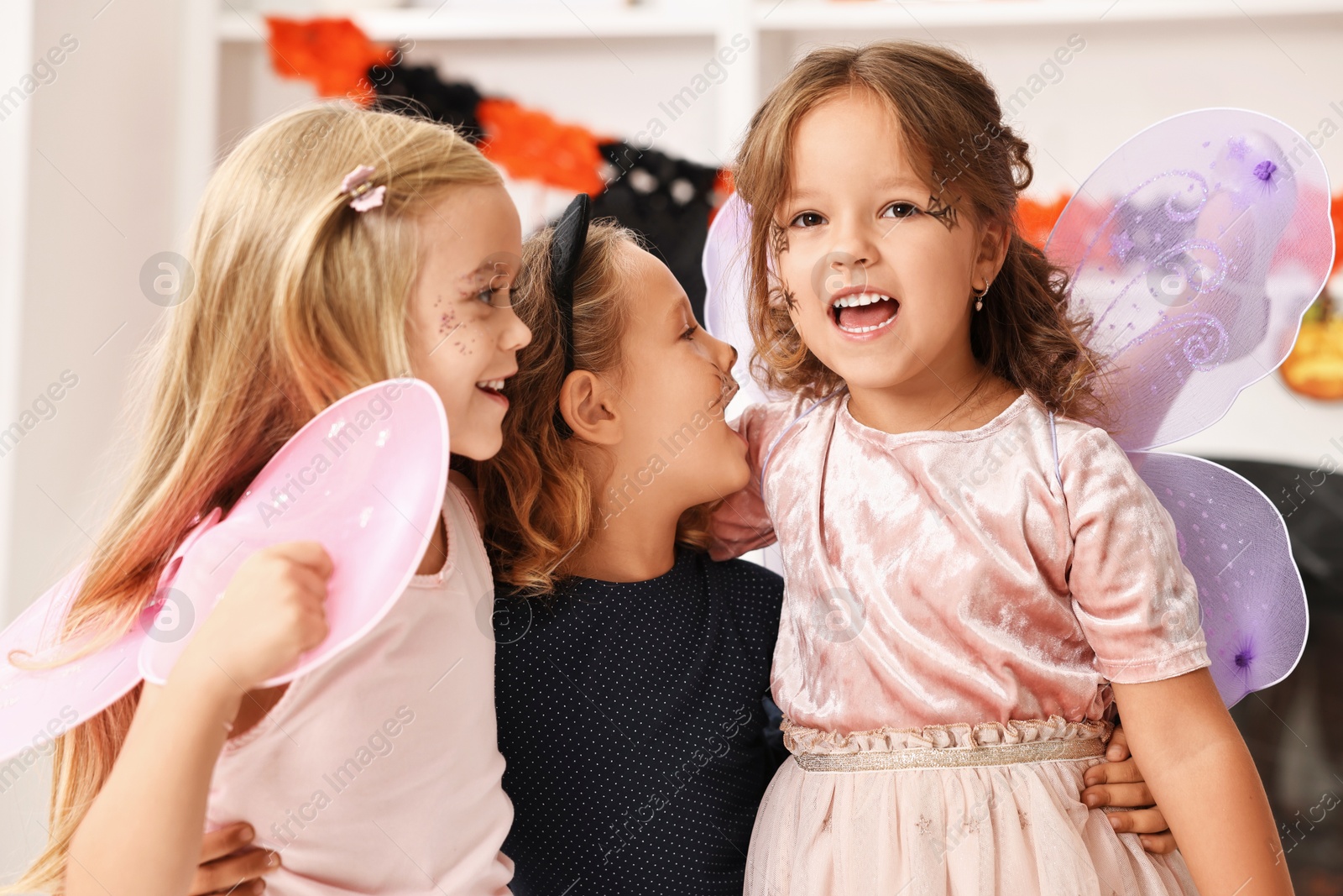 Photo of Cute girls wearing costumes for Halloween celebration indoors