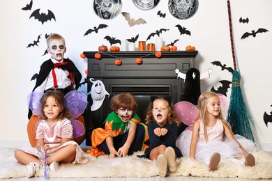 Photo of Funny children wearing costumes for Halloween celebration in decorated room