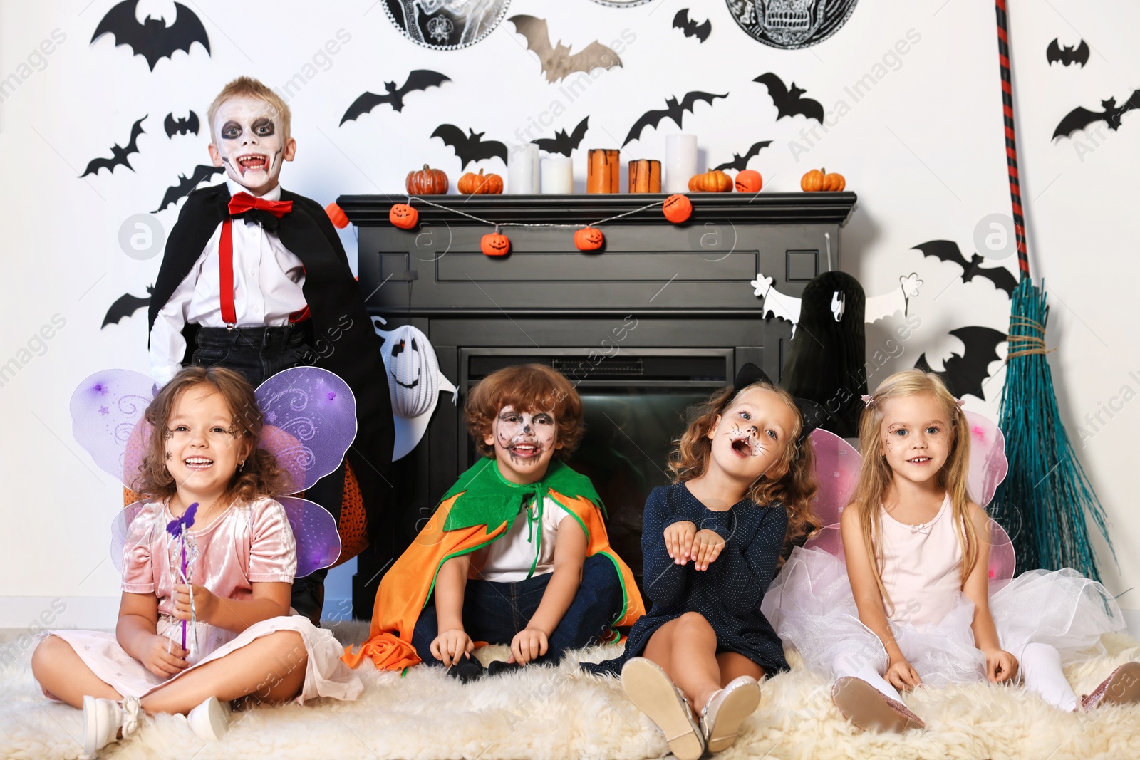 Photo of Funny children in costumes for Halloween celebration in decorated room