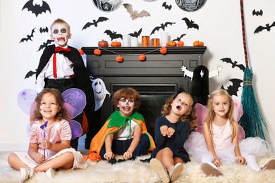 Funny children in costumes for Halloween celebration in decorated room