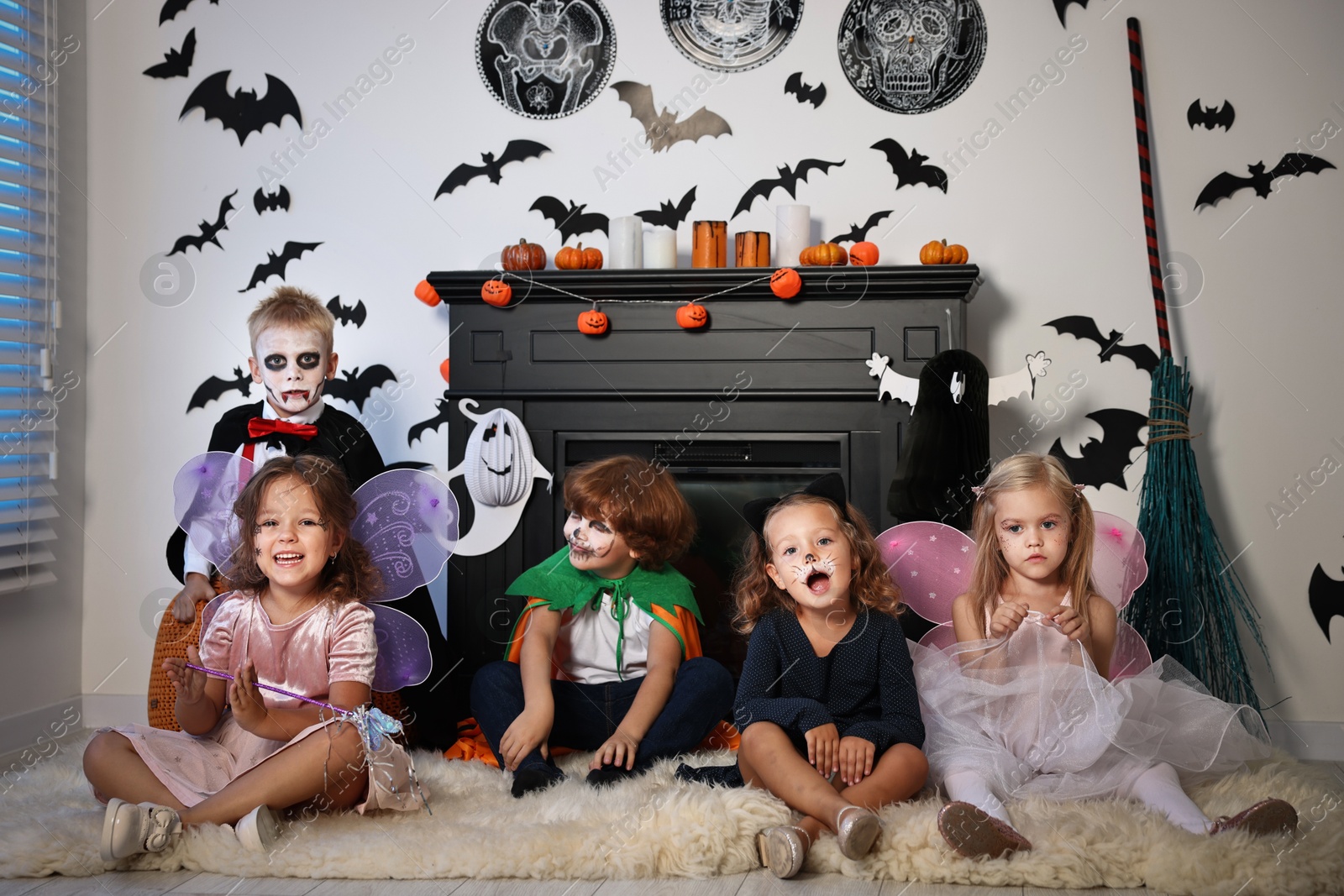 Photo of Funny children in costumes for Halloween celebration in decorated room