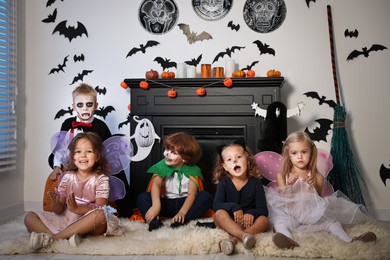 Funny children in costumes for Halloween celebration in decorated room