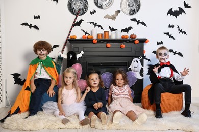 Photo of Funny children wearing costumes for Halloween celebration in decorated room