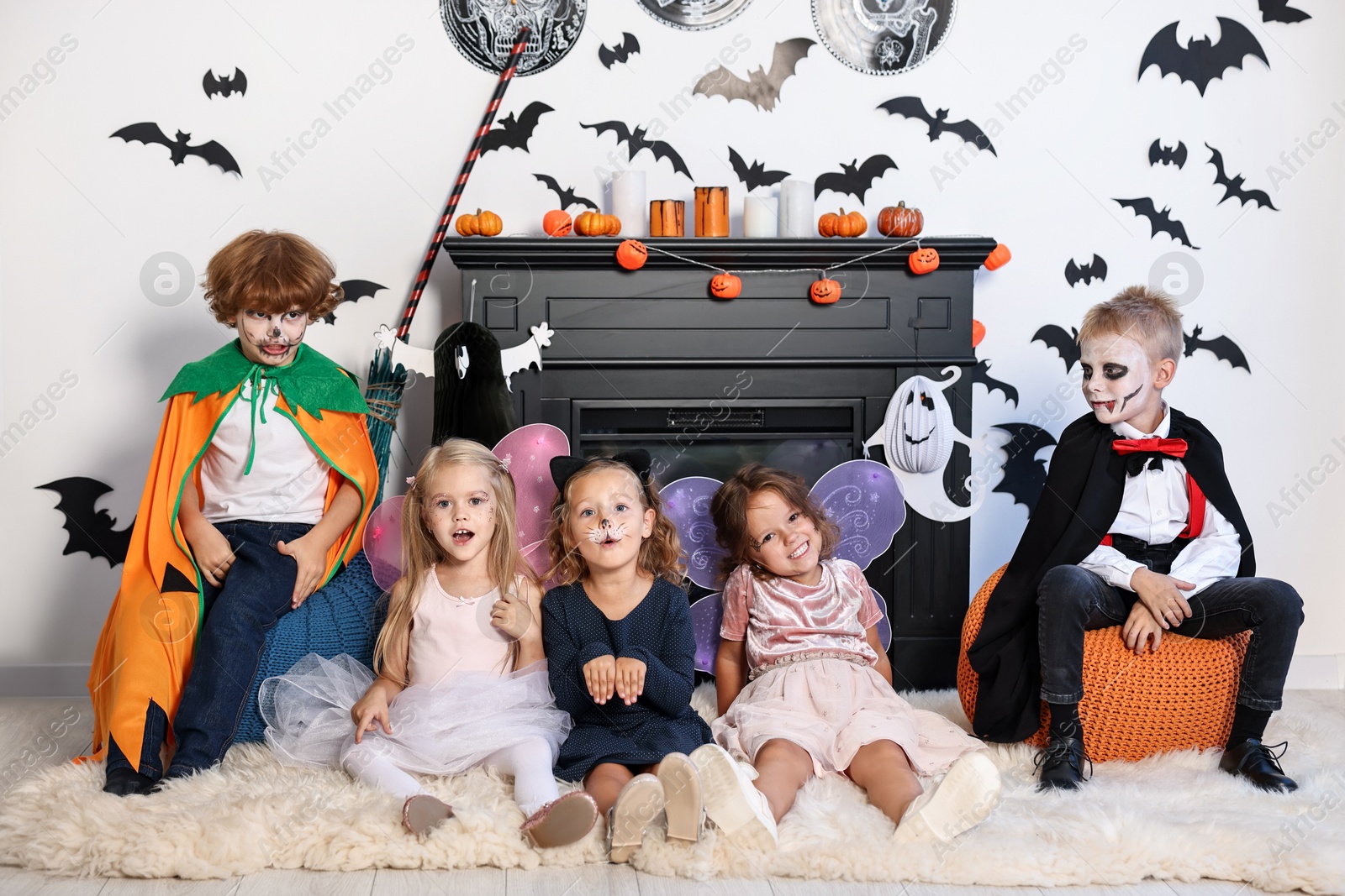 Photo of Funny children in costumes for Halloween celebration in decorated room