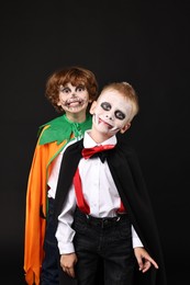 Photo of Funny children wearing costumes for Halloween celebration on black background