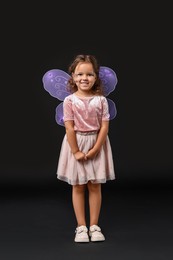 Photo of Cute girl dressed like fairy on black background. Halloween costume