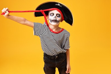 Photo of Funny boy dressed like pirate on yellow background. Halloween costume