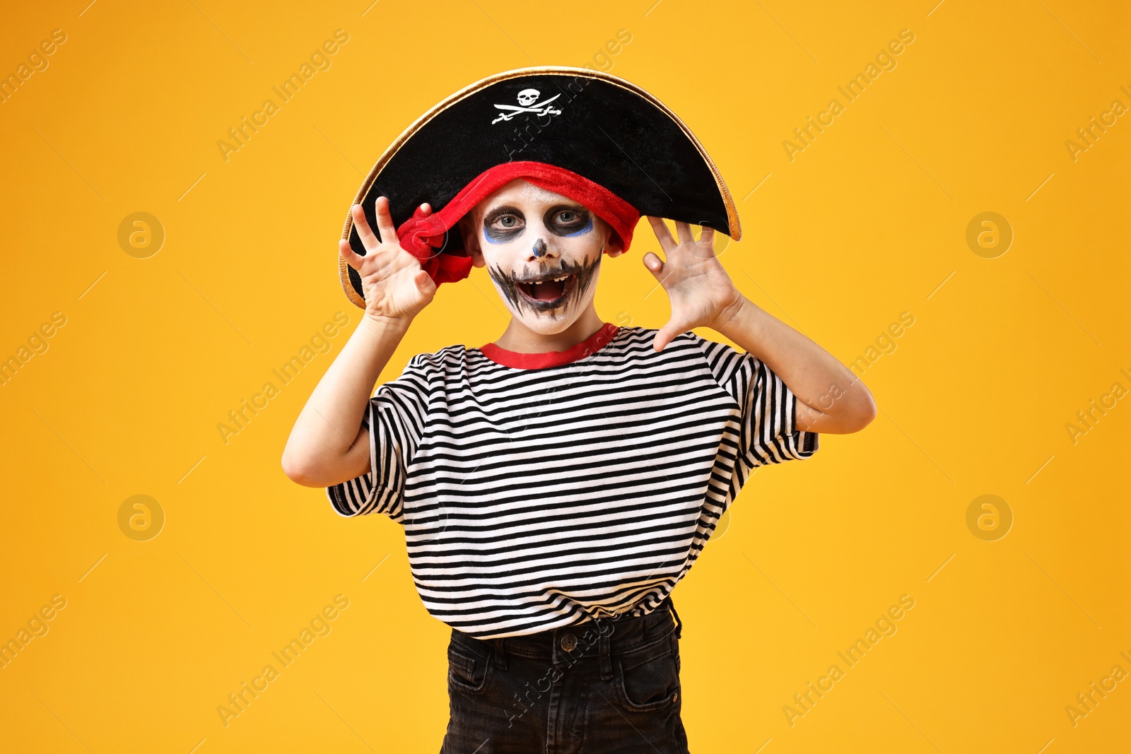 Photo of Funny boy dressed like pirate on yellow background. Halloween costume