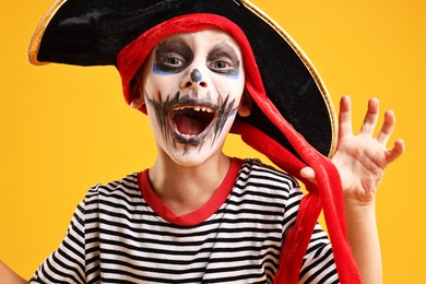 Funny boy dressed like pirate on yellow background. Halloween costume