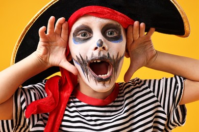 Photo of Funny boy dressed like pirate on yellow background. Halloween costume