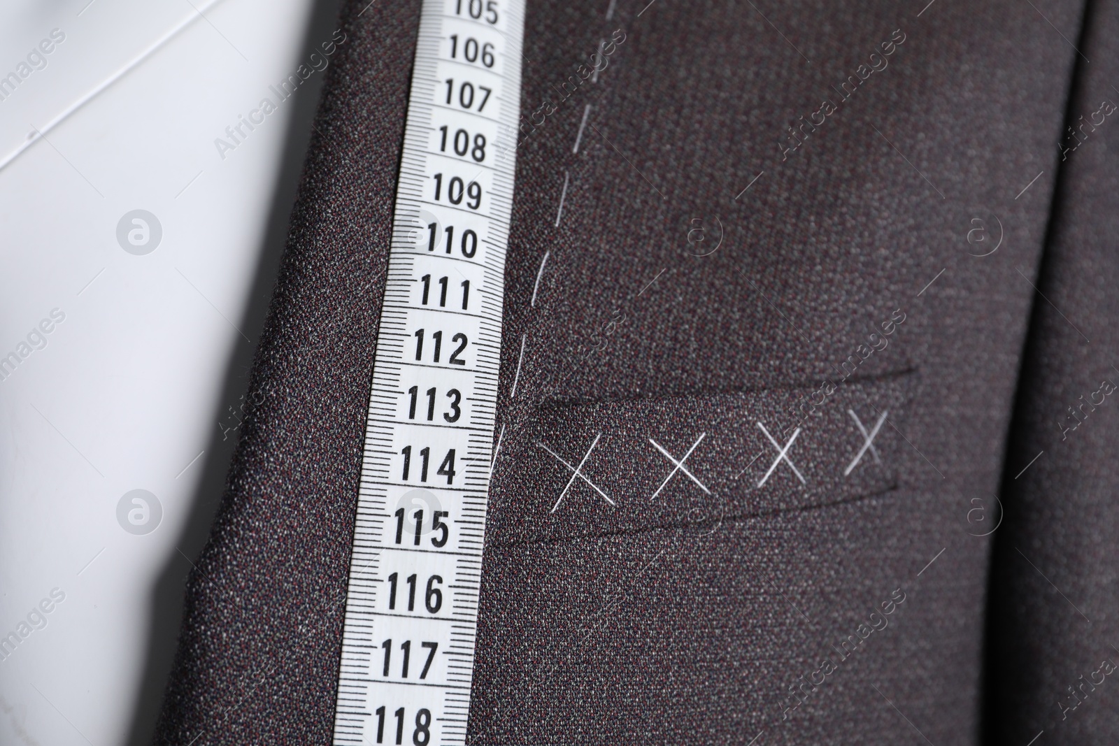 Photo of Semi-ready jacket with tailor's measuring tape on mannequin, closeup