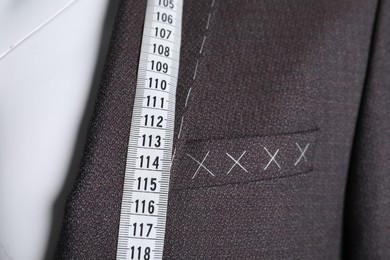 Photo of Semi-ready jacket with tailor's measuring tape on mannequin, closeup