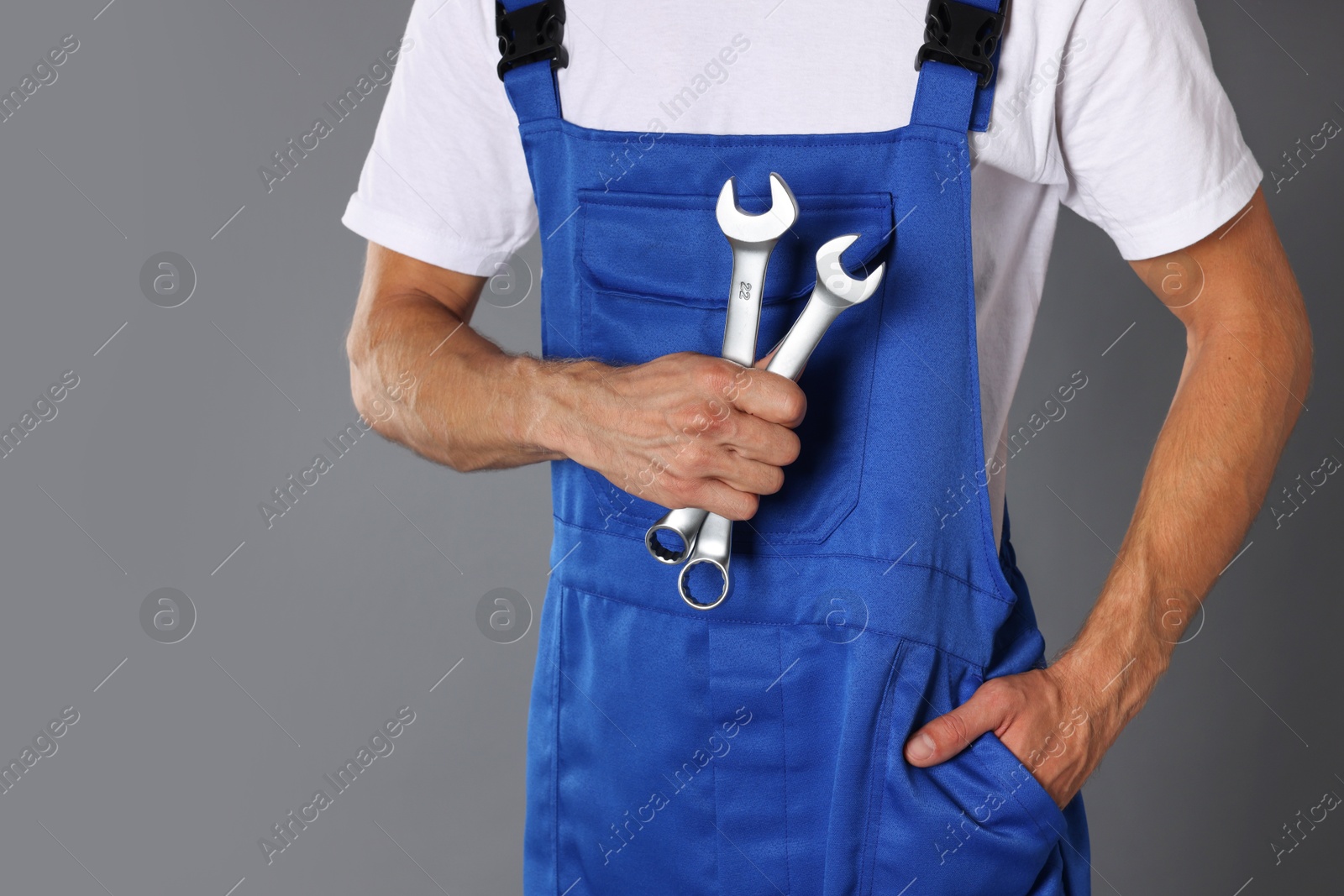 Photo of Auto mechanic with wrenches on grey background, closeup