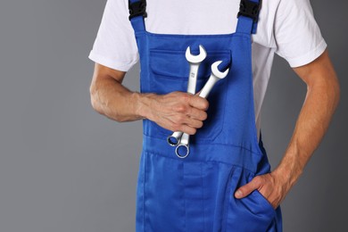 Auto mechanic with wrenches on grey background, closeup