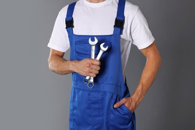 Photo of Auto mechanic with wrenches on grey background, closeup