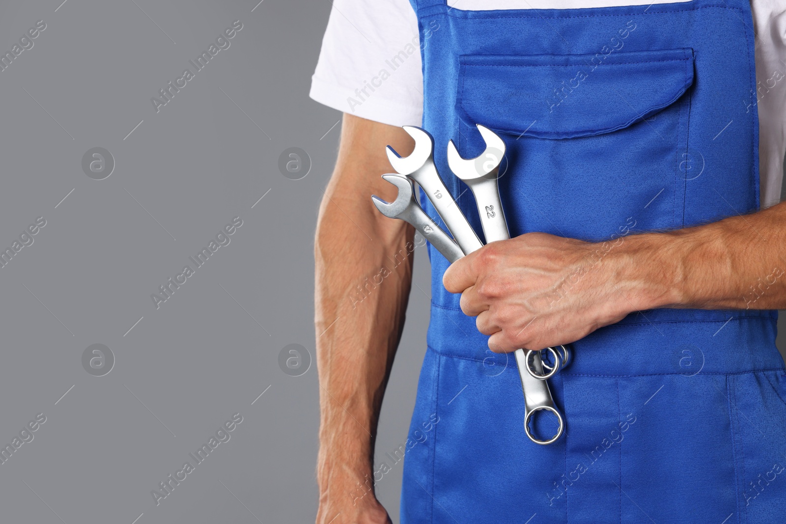 Photo of Auto mechanic with wrenches on grey background, closeup. Space for text