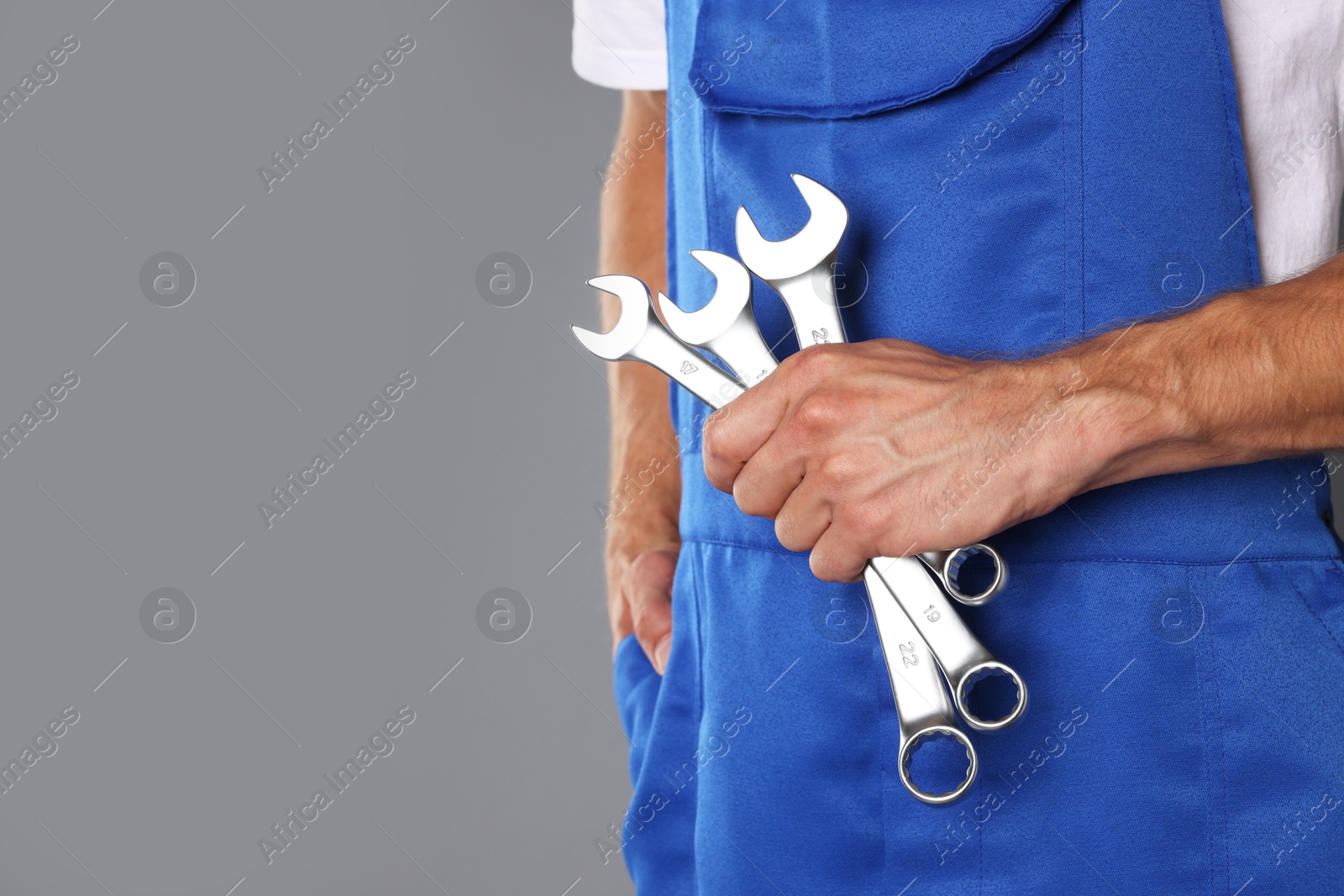 Photo of Auto mechanic with wrenches on grey background, closeup. Space for text