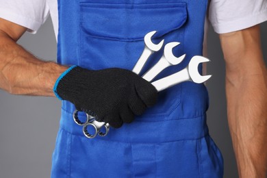 Photo of Auto mechanic with wrenches on grey background, closeup