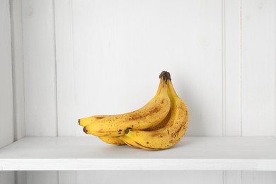 Photo of Bunch of ripe bananas with dark spots on shelf