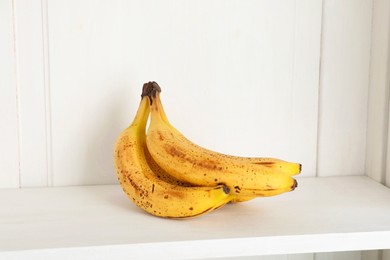 Photo of Bunch of ripe bananas with dark spots on shelf