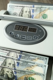 Photo of Money counter machine with dollar banknotes, closeup