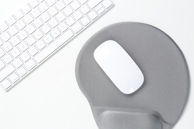 Photo of Keyboard, mouse and mousepad with arm rest on white table, top view