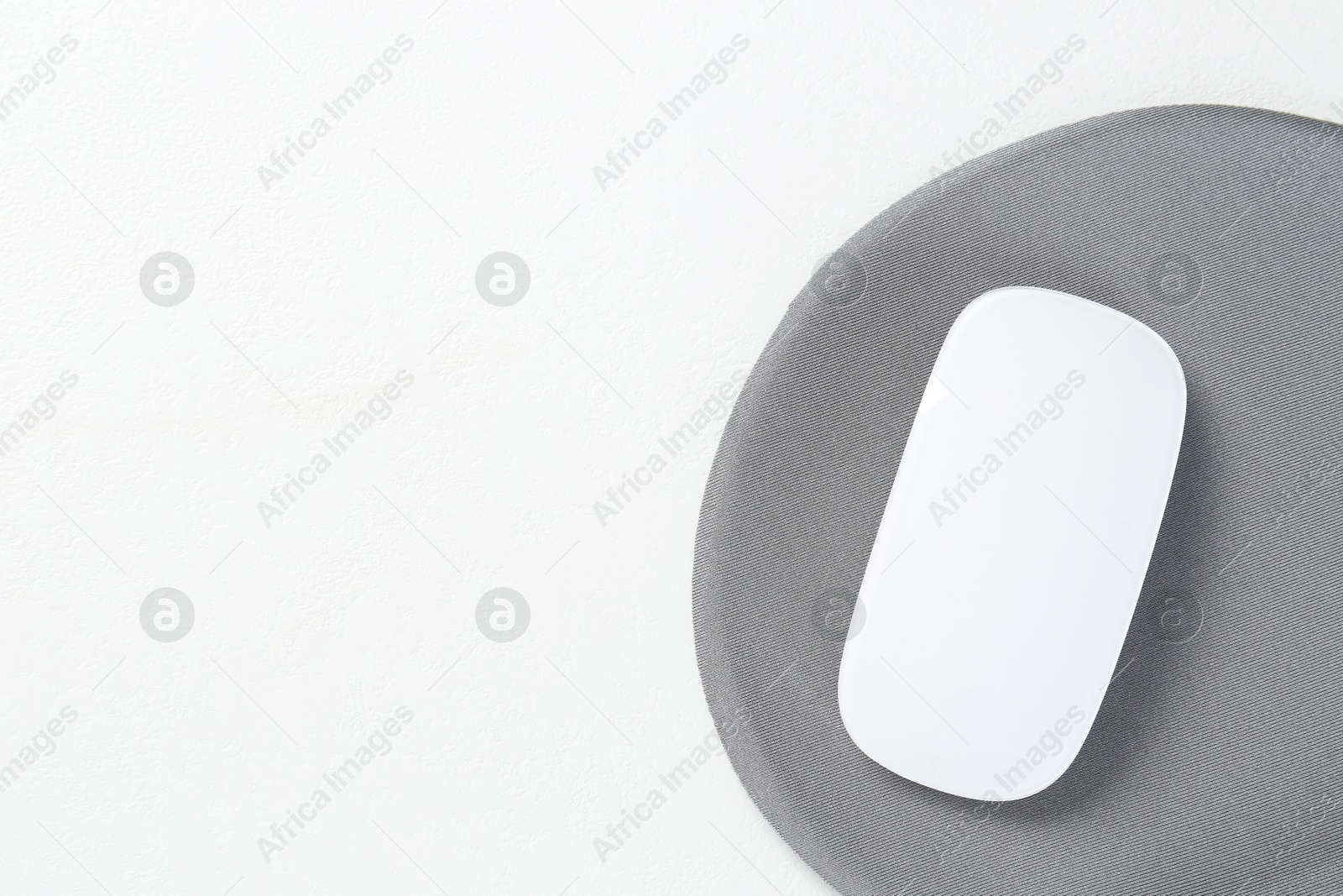 Photo of Mouse and mousepad on white table, top view. Space for text