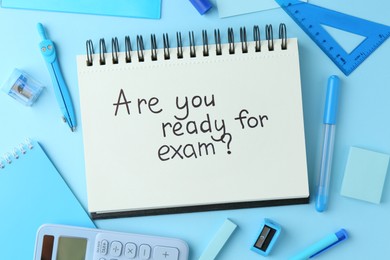 Photo of Notepad with question Are You Ready For Exam and stationery on light blue background, flat lay