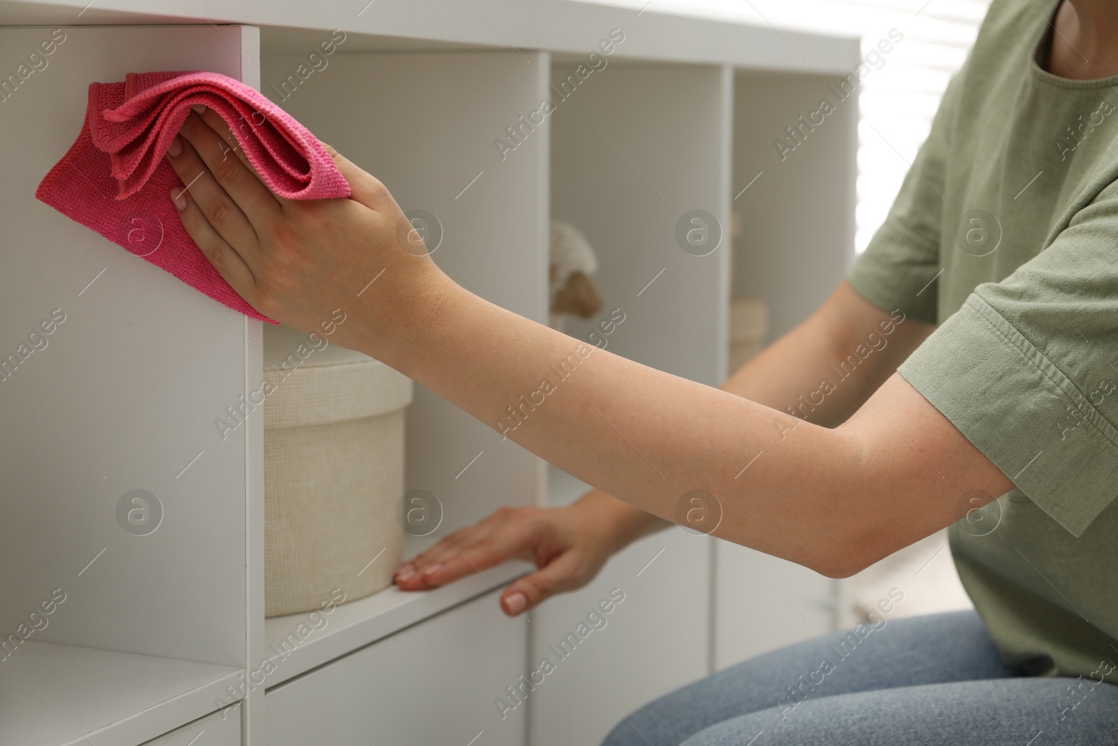 Photo of Woman wiping furniture with rag indoors, closeup