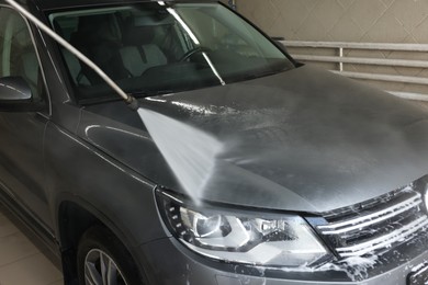 Washing auto with high pressure water jet at car wash, closeup