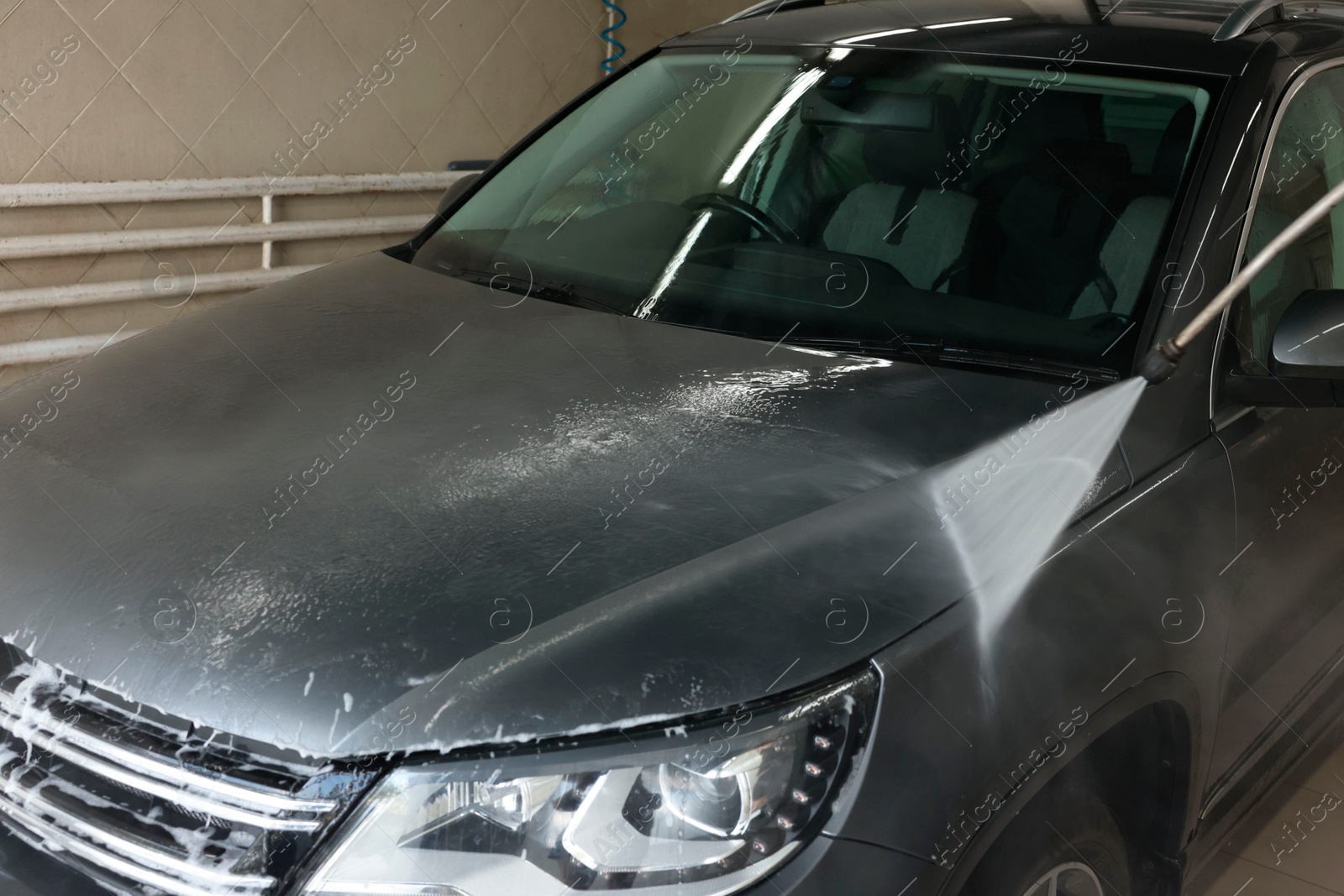 Photo of Washing auto with high pressure water jet at car wash, closeup