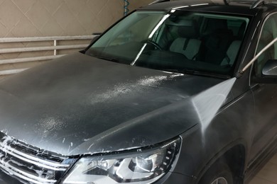 Washing auto with high pressure water jet at car wash, closeup