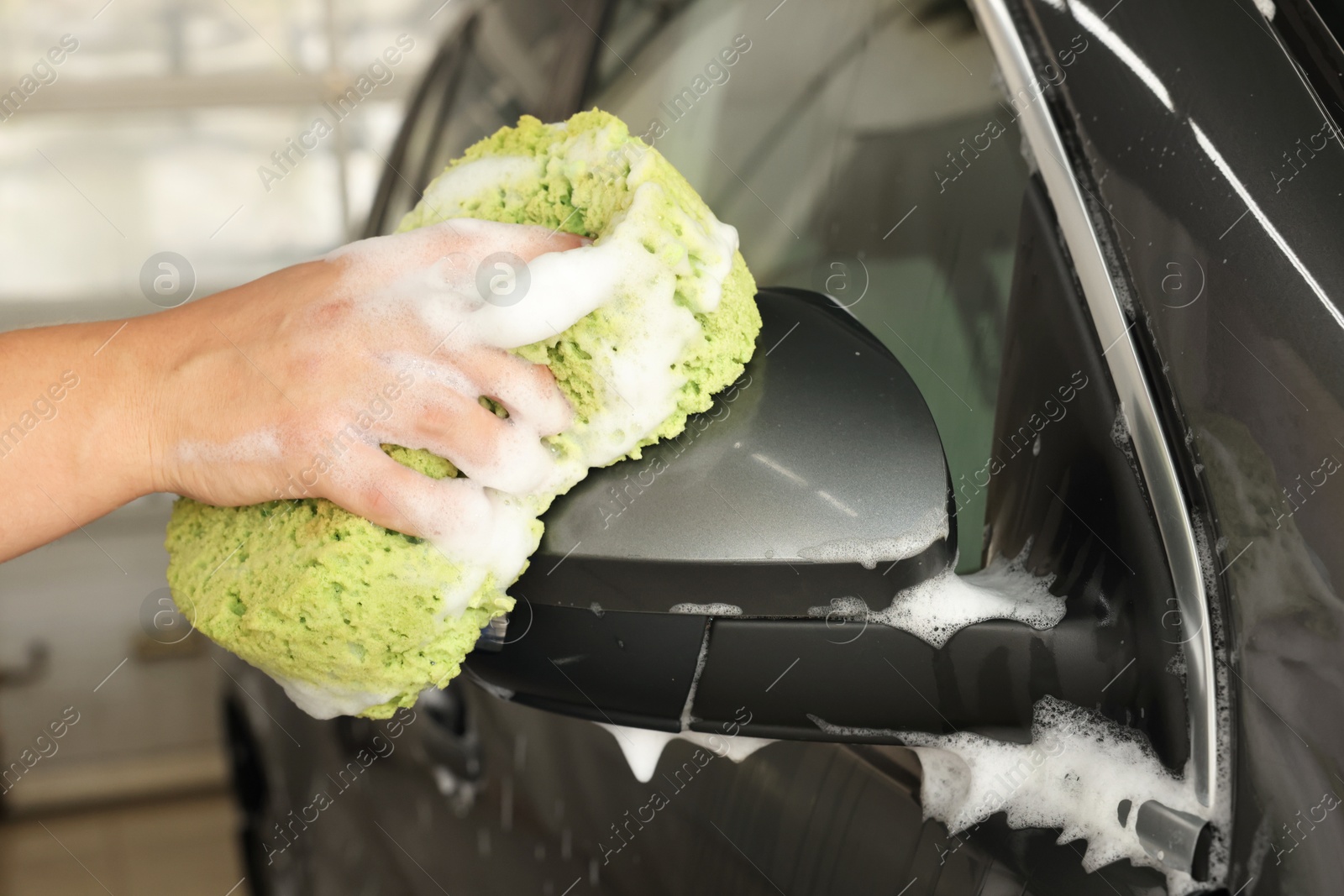 Photo of Man washing auto with sponge at car wash, closeup