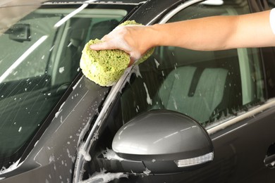 Photo of Man washing auto with sponge at car wash, closeup